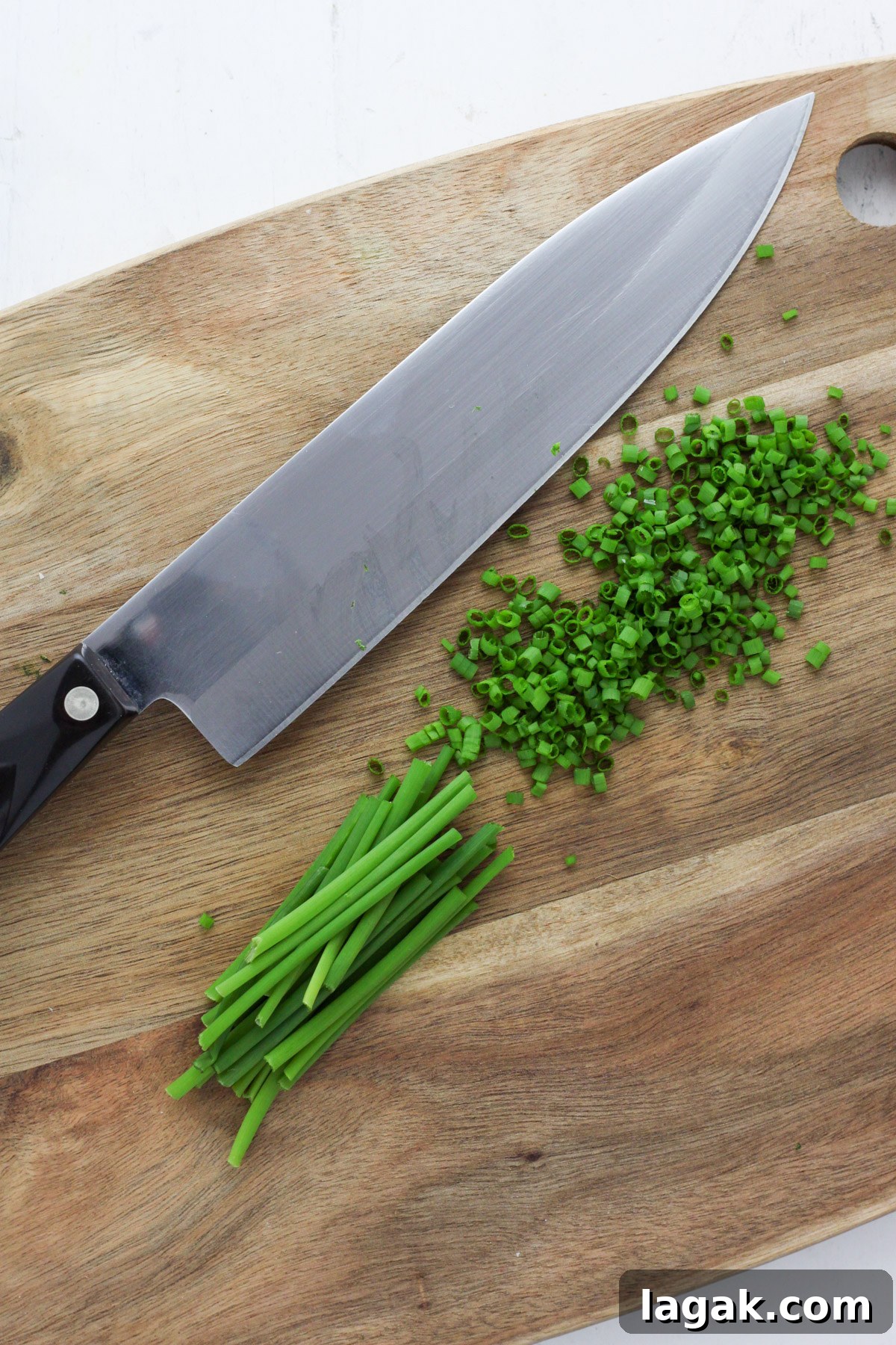 Creamy Sour Cream & Chive Dip Recipe for Parties 3 A wooden cutting board with a knife and chopped chives.