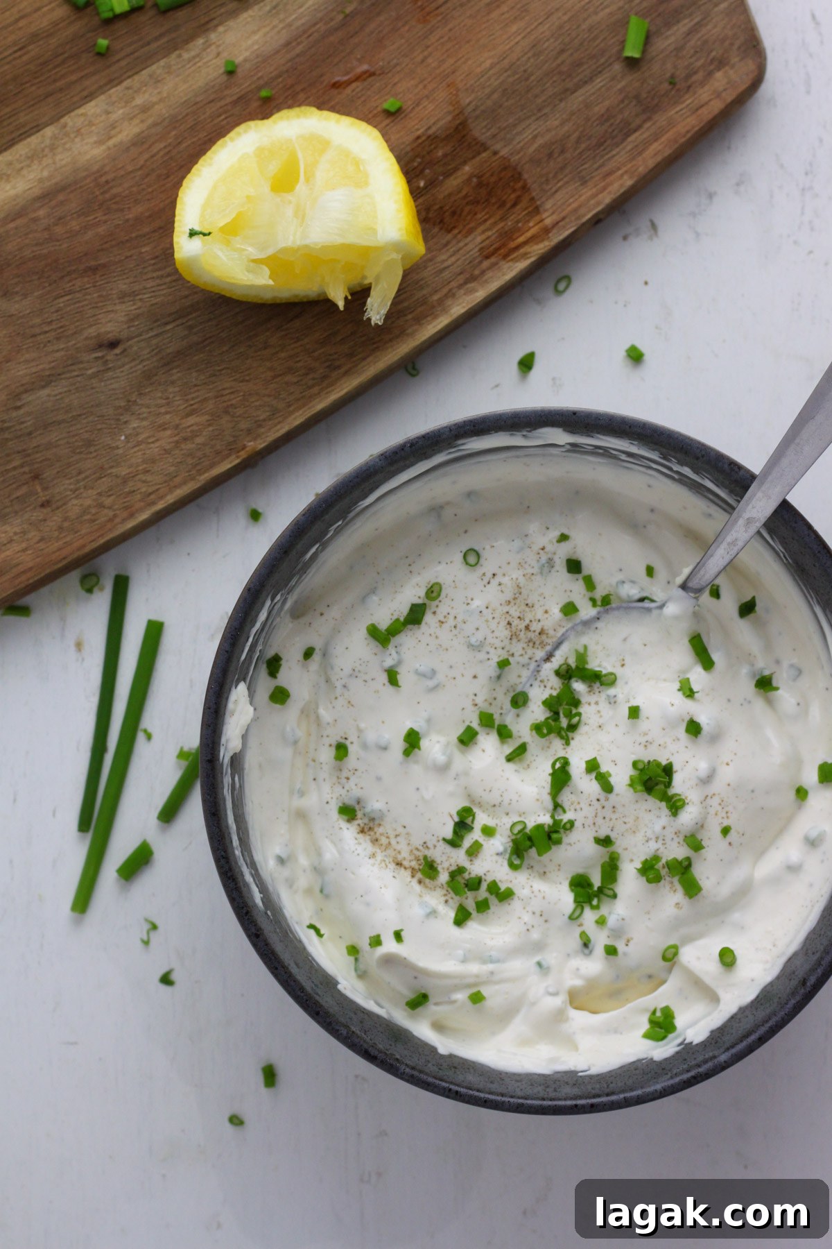 Creamy Sour Cream & Chive Dip Recipe for Parties 6 A blue bowl with sour cream and chive dip and a spoon.