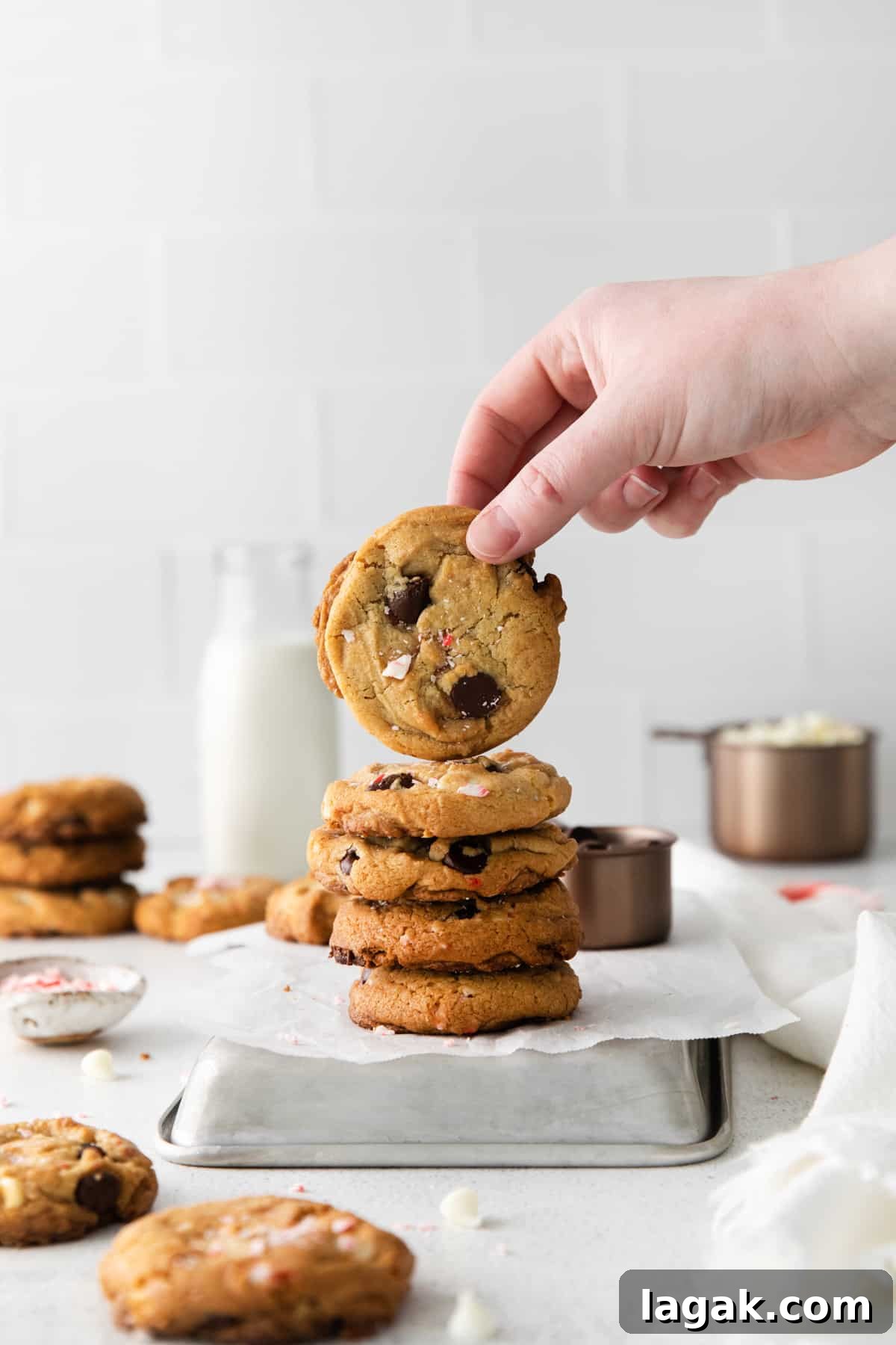 Peppermint Chocolate Chip Cookie Recipe: Crisp, Minty Holiday Cookies 2 hand lifting a peppermint chocolate chip cookie from a stack.