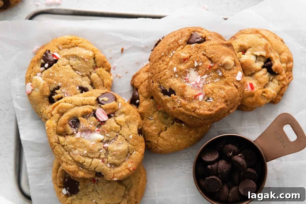 Peppermint Chocolate Chip Cookie Recipe: Crisp, Minty Holiday Cookies 3 overhead view of a pile of peppermint chocolate chip cookies on a baking sheet next to a measuring cup filled with chocolate chips.