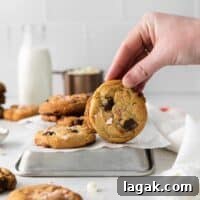 Peppermint Chocolate Chip Cookie Recipe: Crisp, Minty Holiday Cookies 4 hand holding a peppermint chocolate chip cookie upright on an inverted baking tray.