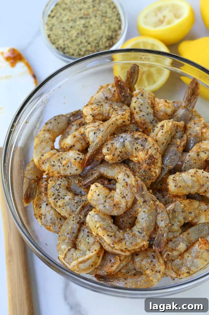Shrimp in a bowl with lemon pepper seasoning and fresh lemons