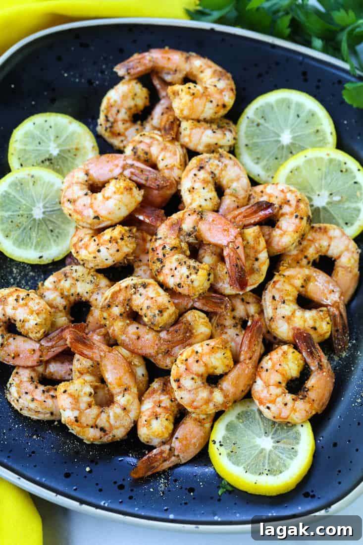 Air Fryer Lemon Pepper Shrimp on a black serving plate with lemon slices