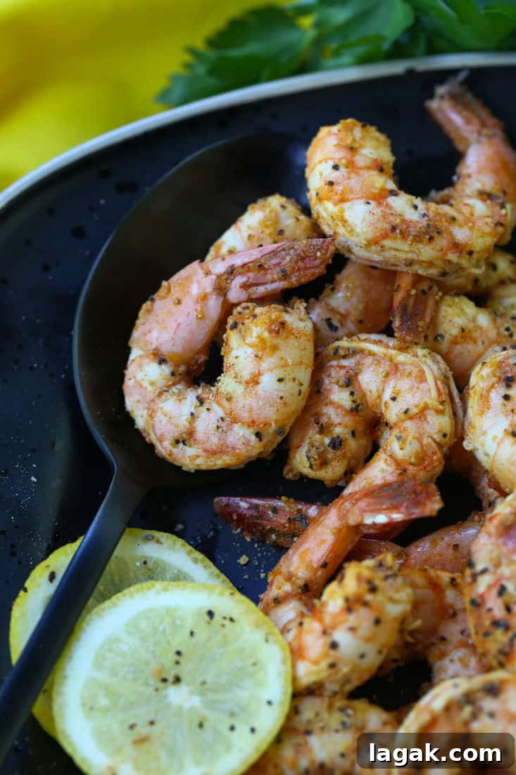 Shrimp on a black plate with a serving spoon