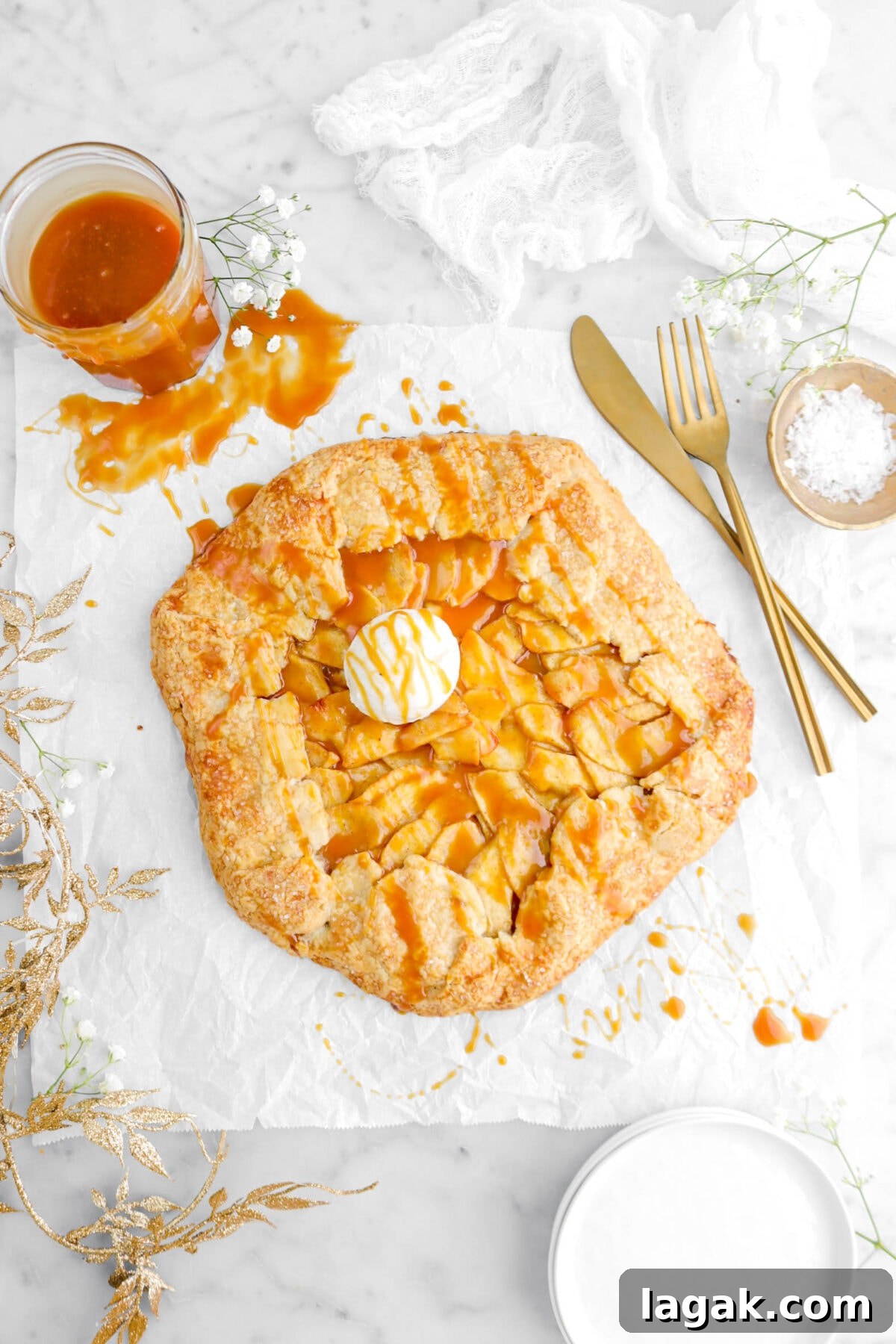 Caramel Apple Galette Recipe: Rustic Fall Dessert with Salty Caramel 4 overhead shot of caramel apple galette with scoop of ice cream on top, gold garland beside, and gold fork and knife beside
