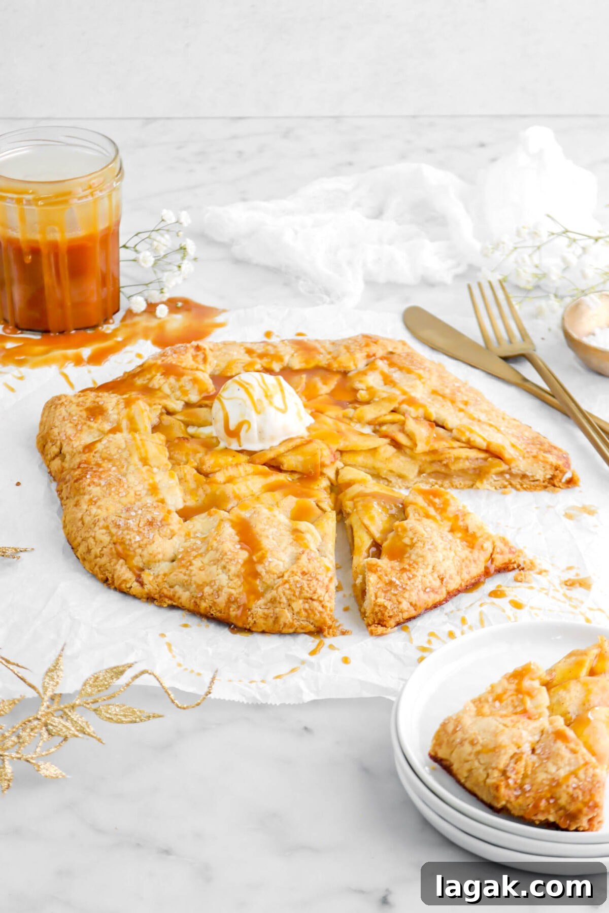 Caramel Apple Galette Recipe: Rustic Fall Dessert with Salty Caramel 20 front shot of galette on parchment paper with slice on stacked plates with jar behind and white cheesecloth