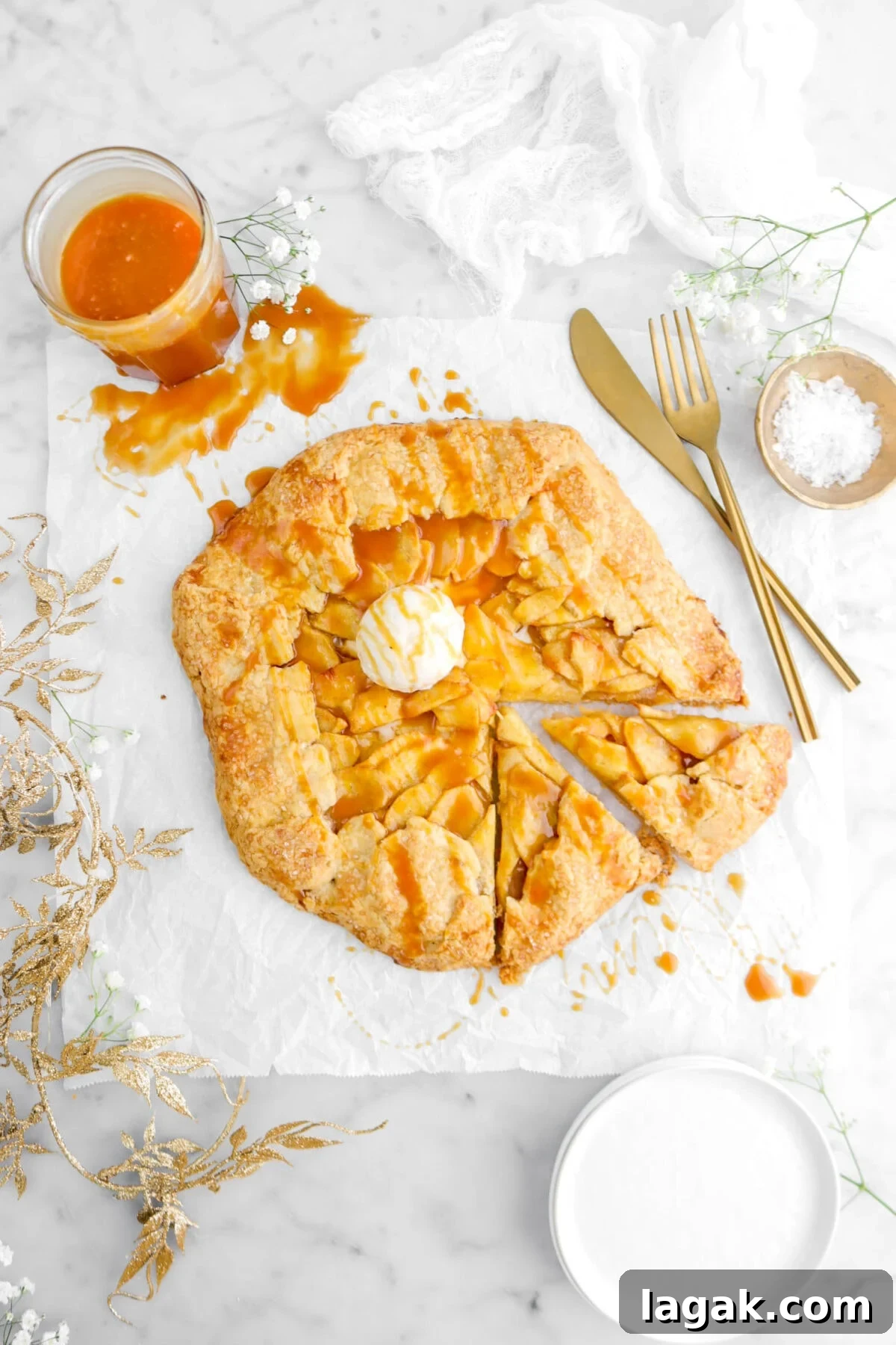 Caramel Apple Galette Recipe: Rustic Fall Dessert with Salty Caramel 23 overhead shot of caramel apple galette with two slices cut from it on parchment paper with a scoop of ice cream on top