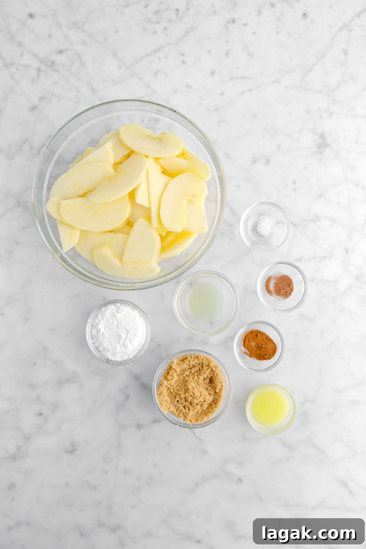 Caramel Apple Galette Recipe: Rustic Fall Dessert with Salty Caramel 9 apple slices, cornstarch, brown sugar, lemon juice, salt, nutmeg, cinnamon, and melted butter on marble surface
