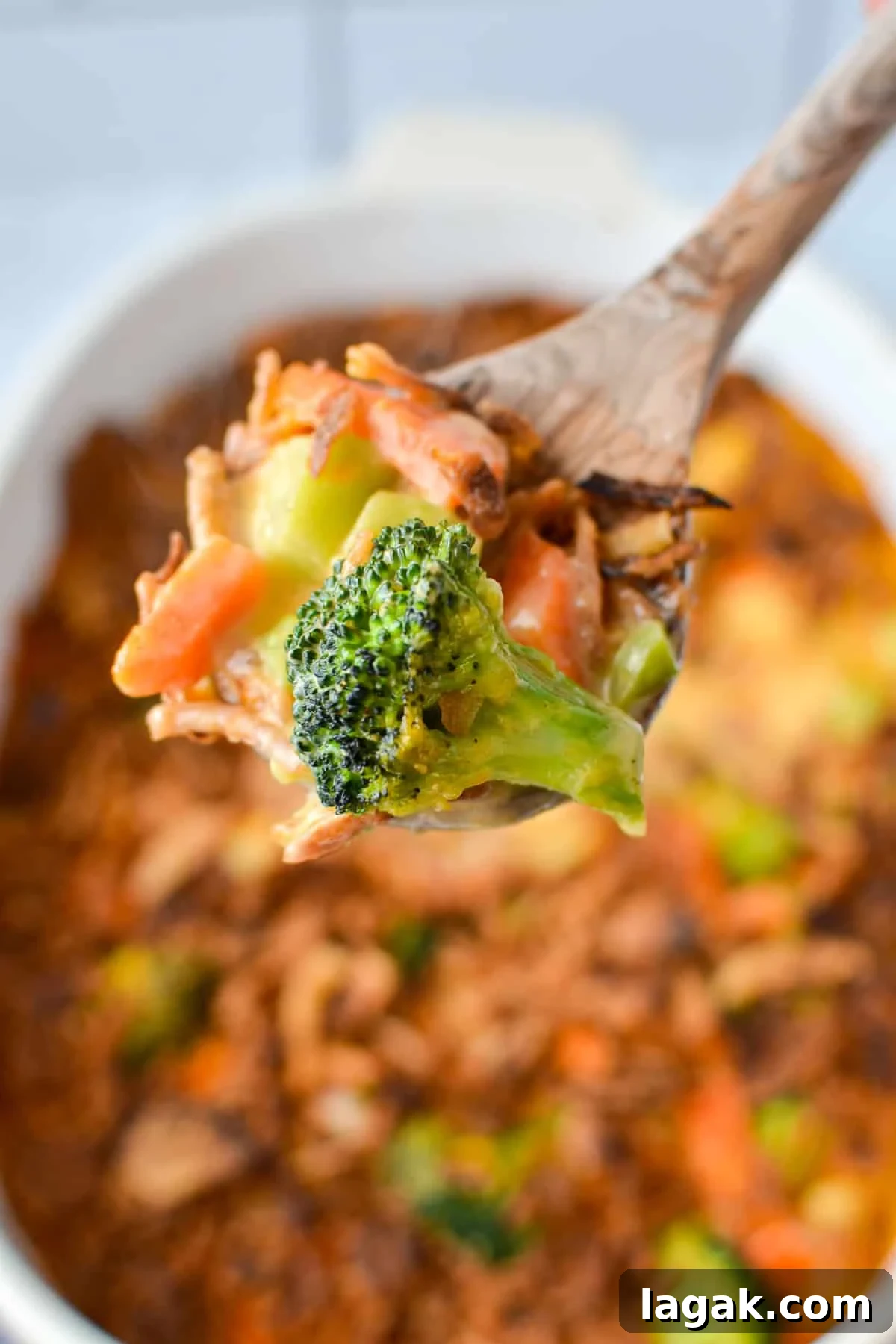 Scooping vegetable casserole with a wooden spoon.