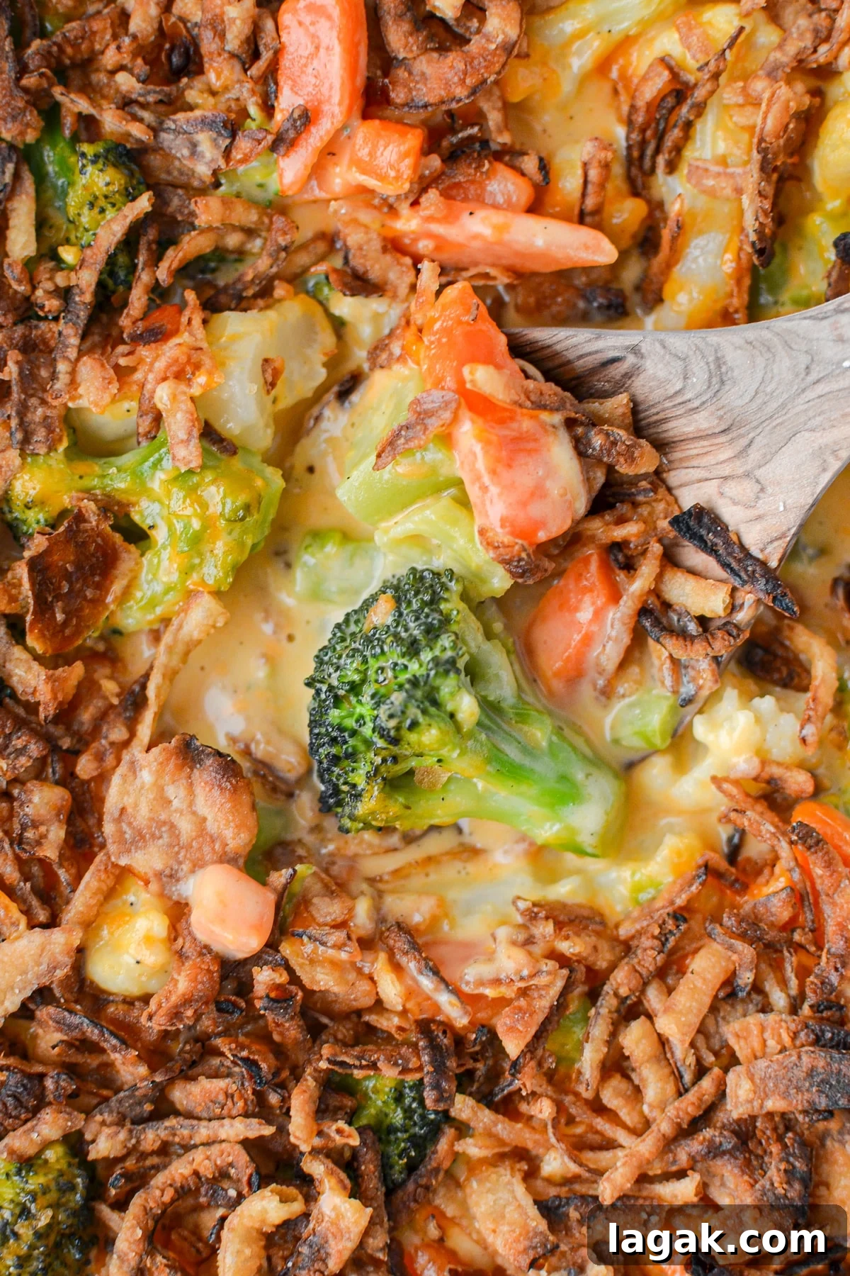 A wooden spoon scooping out a casserole with broccoli.