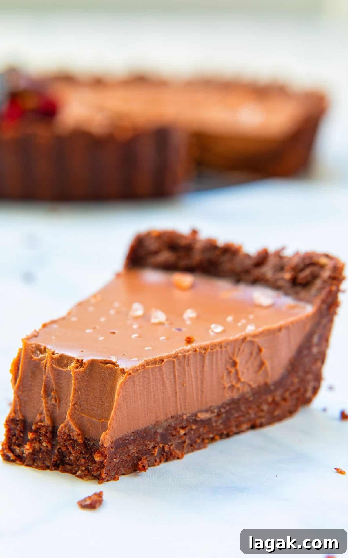 Decadent Vegan Chocolate Tart Recipe for Rich, Creamy Desserts 9 Close up of a sliced vegan chocolate tart from front angle with a bite taken.
