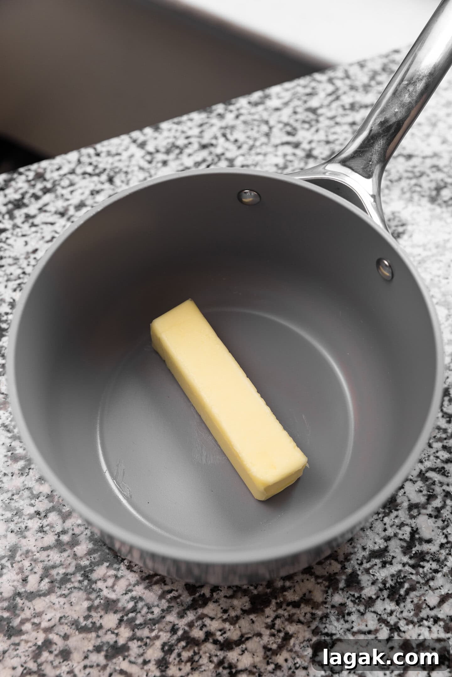 A stick of butter being melted down in a saucepan. 