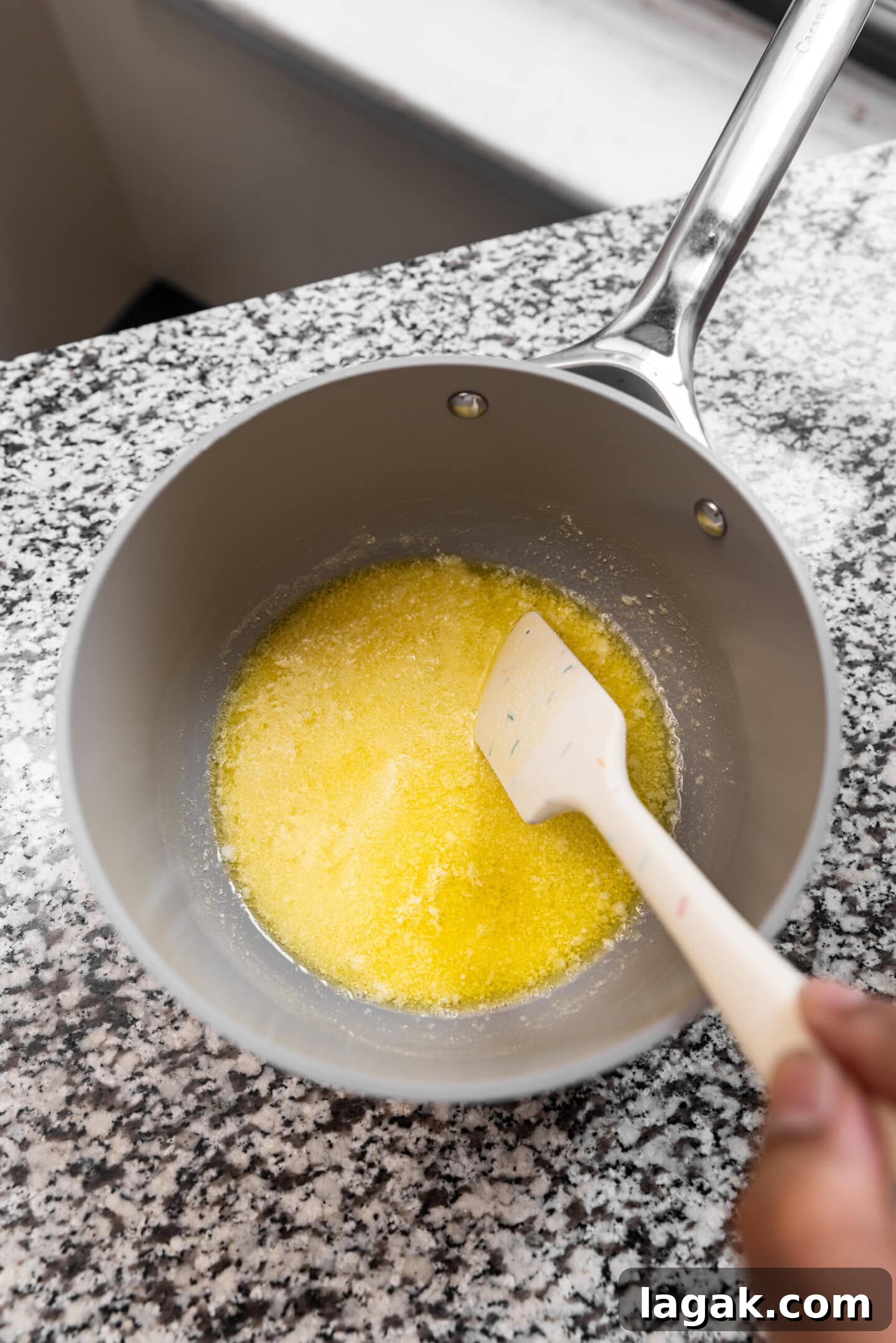 Dry milk powder being stirred into melted butter.