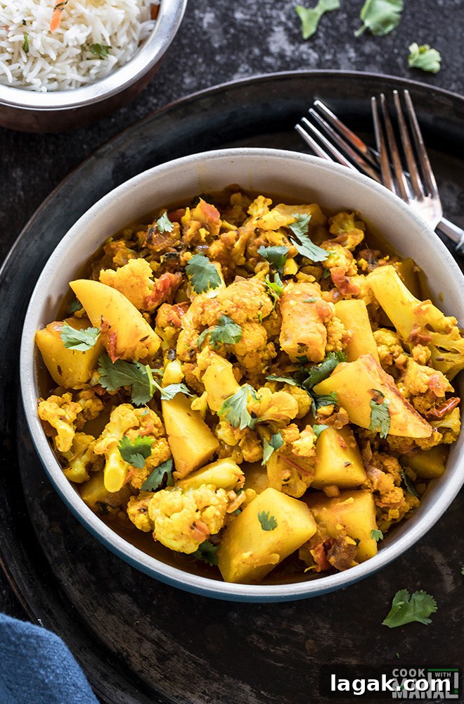Instant Pot Aloo Gobi: Quick Spiced Potato & Cauliflower Curry 5 Instant Pot Aloo Gobi served in a blue bowl with forks on the side and rice in the background