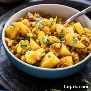 Instant Pot Aloo Gobi: Quick Spiced Potato & Cauliflower Curry 9 bowl of aloo gobi with a spoon and bowl of rice in the background