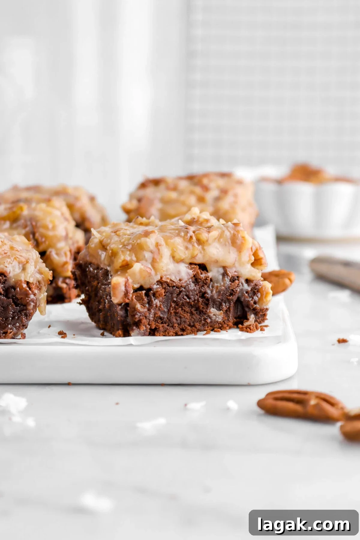 close up of german chocolate brownie on white tray with more behind.