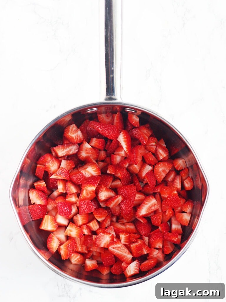 Strawberry Jam Recipe with Pectin: Smooth, Spreadable Preserves 5 Sliced strawberries in a metal saucepan.