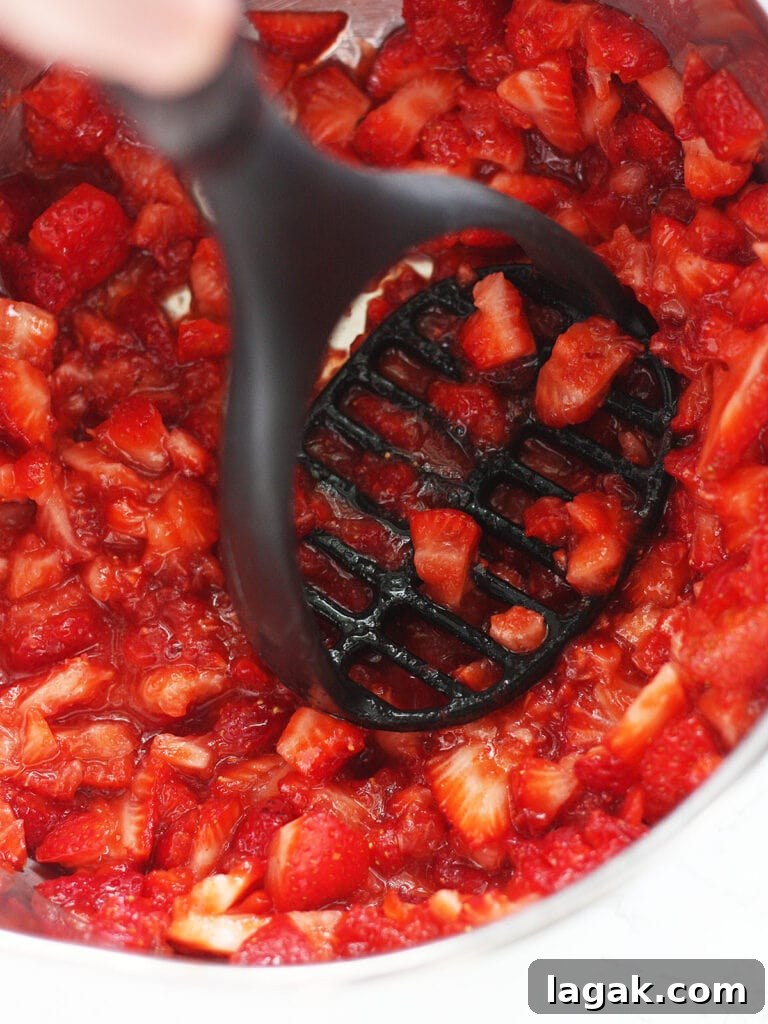 Strawberry Jam Recipe with Pectin: Smooth, Spreadable Preserves 6 Mashing cut up strawberries with a potato masher.