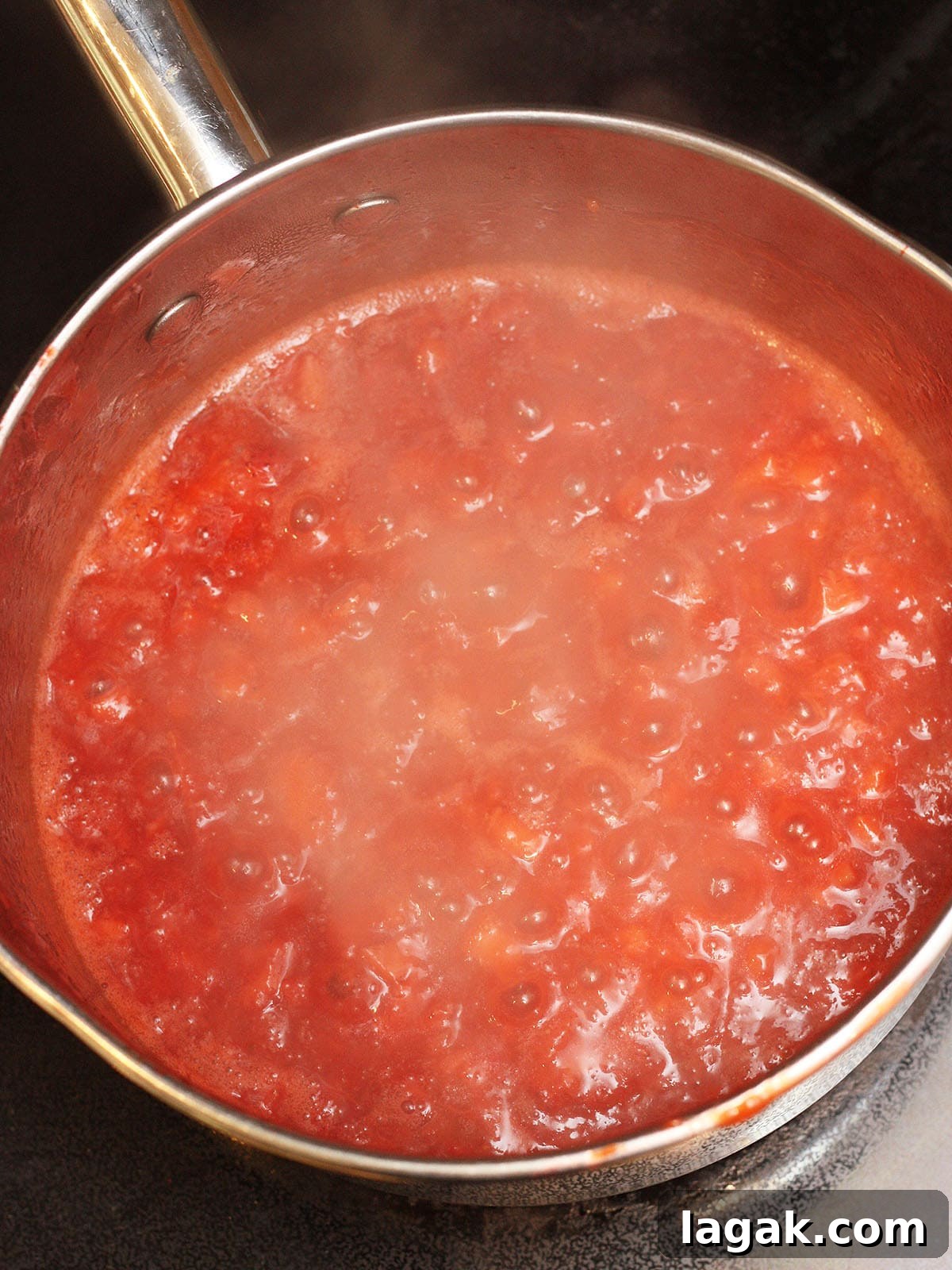Strawberry Jam Recipe with Pectin: Smooth, Spreadable Preserves 9 Homemade strawberry preserves at a full rolling boil in a metal saucepan.