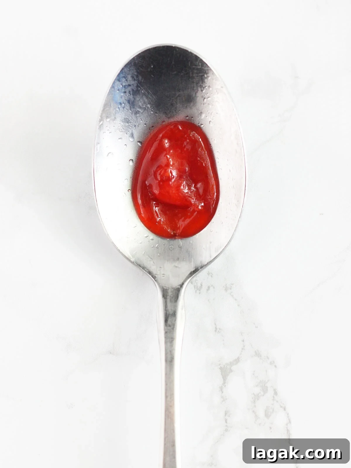 Strawberry Jam Recipe with Pectin: Smooth, Spreadable Preserves 10 Drop of strawberry preserves in the middle of a cold metal spoon.