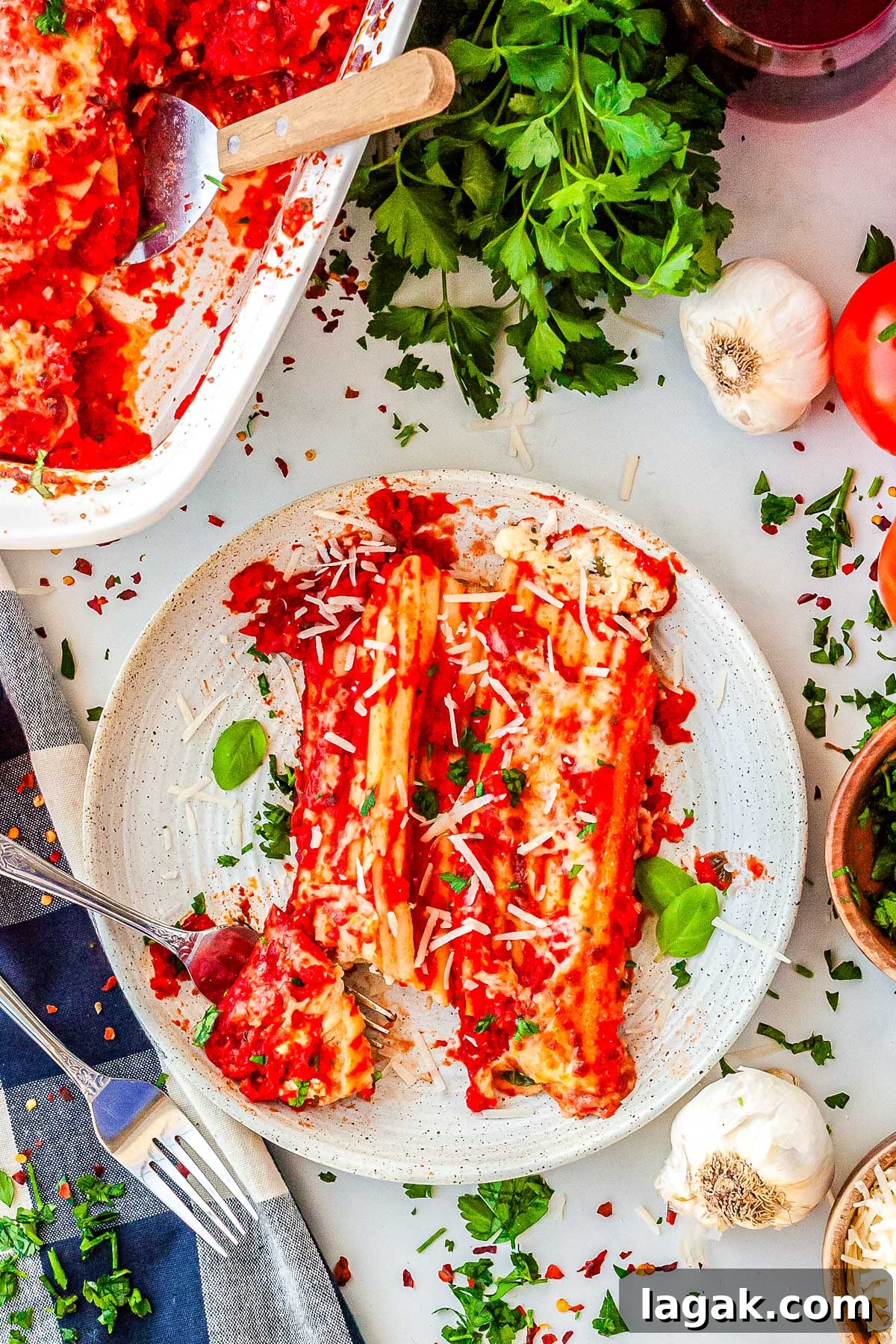 Creamy Three-Cheese Manicotti with Homemade Tomato Sauce 2 A plated serving of two manicotti rolls covered in red sauce and cheese, cut open with a fork to show the white ricotta filling inside.