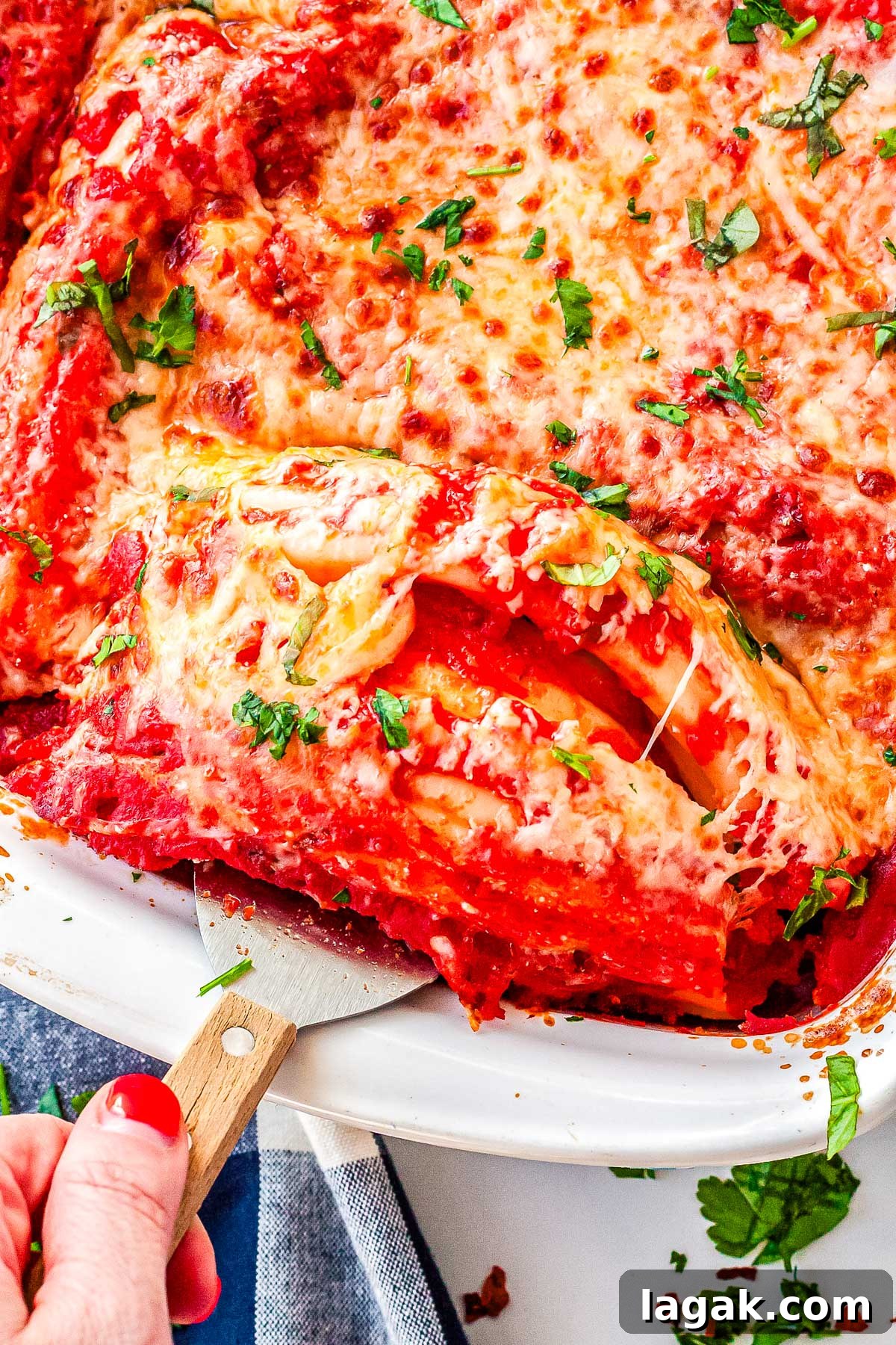 Creamy Three-Cheese Manicotti with Homemade Tomato Sauce 11 A close-up shot of a spatula lifting a cheesy manicotti roll out of the baking dish, revealing the saucy layers and creamy interior.