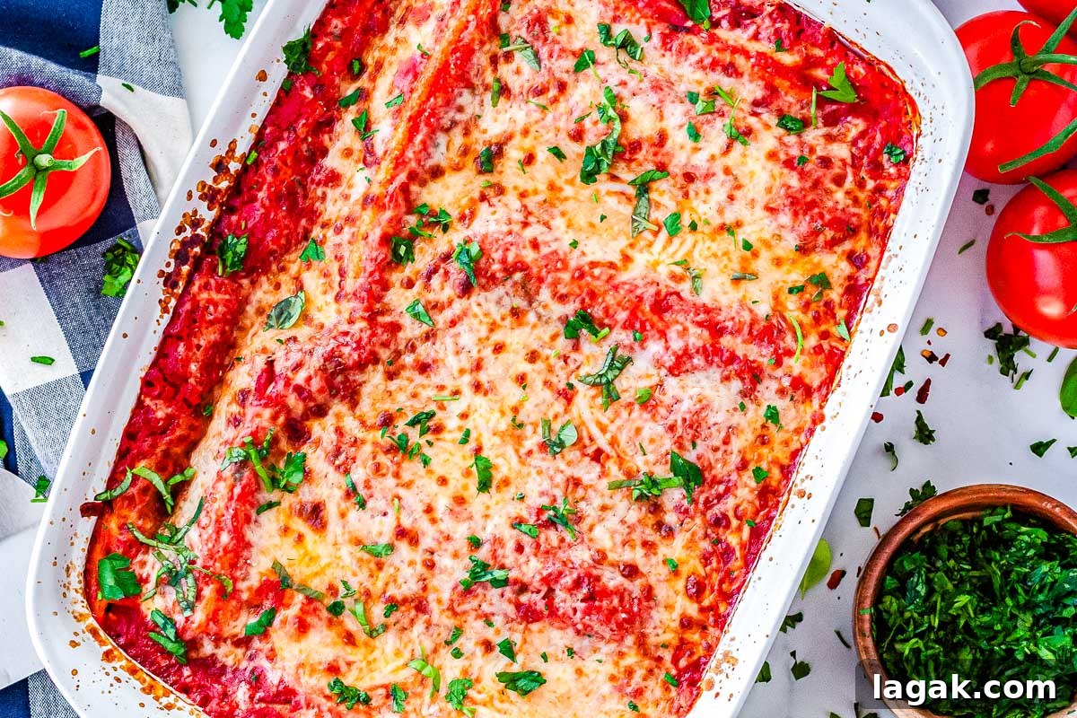 Creamy Three-Cheese Manicotti with Homemade Tomato Sauce 3 An overhead view of the full baked casserole dish, featuring golden melted cheese, rich tomato sauce, and a garnish of fresh chopped basil.