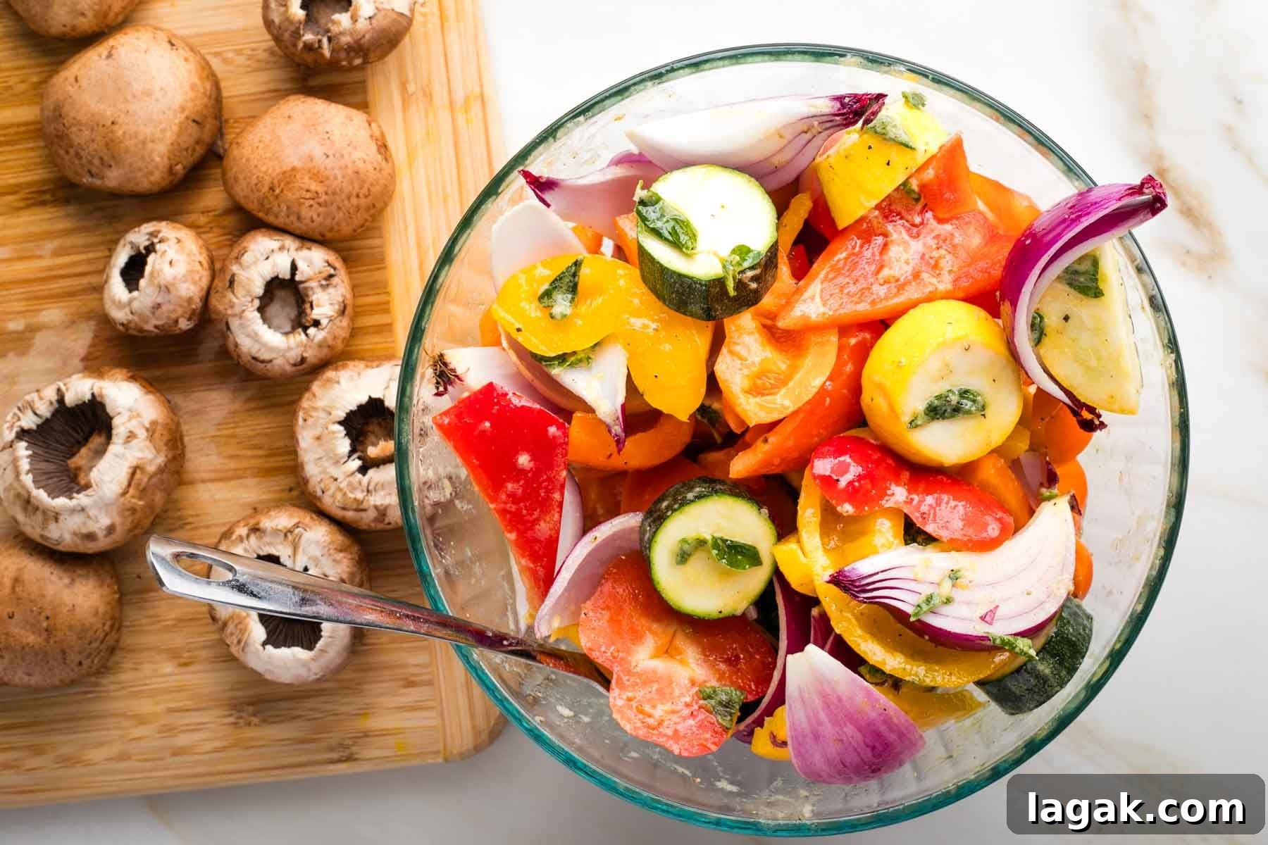 Bowl of cut up veggies marinating and a cutting board with mushrooms off to the side.