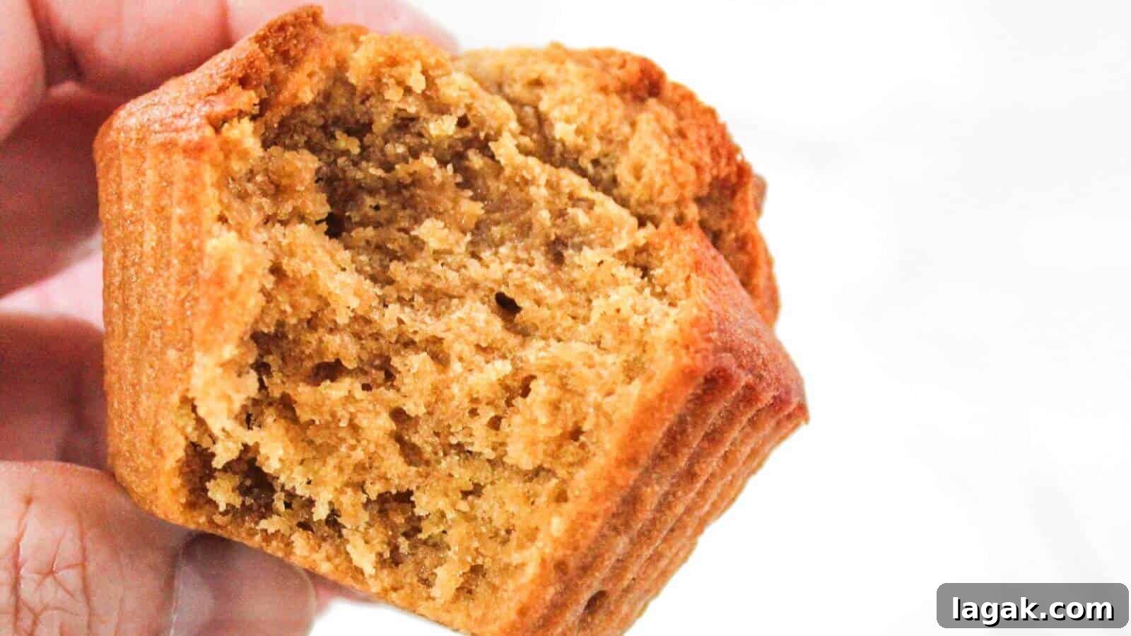 29 Party-Worthy Treats That Won’t Leave Leftovers 19 A person holds a partially eaten, golden-brown muffin, showcasing its fluffy and moist texture.