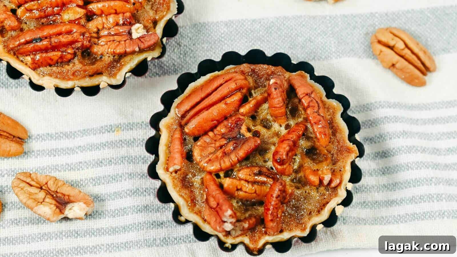 29 Party-Worthy Treats That Won’t Leave Leftovers 29 Two pecan pie tarts placed on a striped cloth with scattered pecans around them.