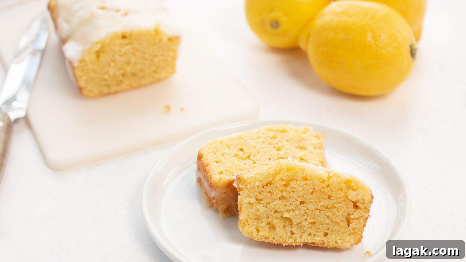 29 Party-Worthy Treats That Won’t Leave Leftovers 6 Slices of lemon loaf with icing on a white plate, with whole lemons in the background.