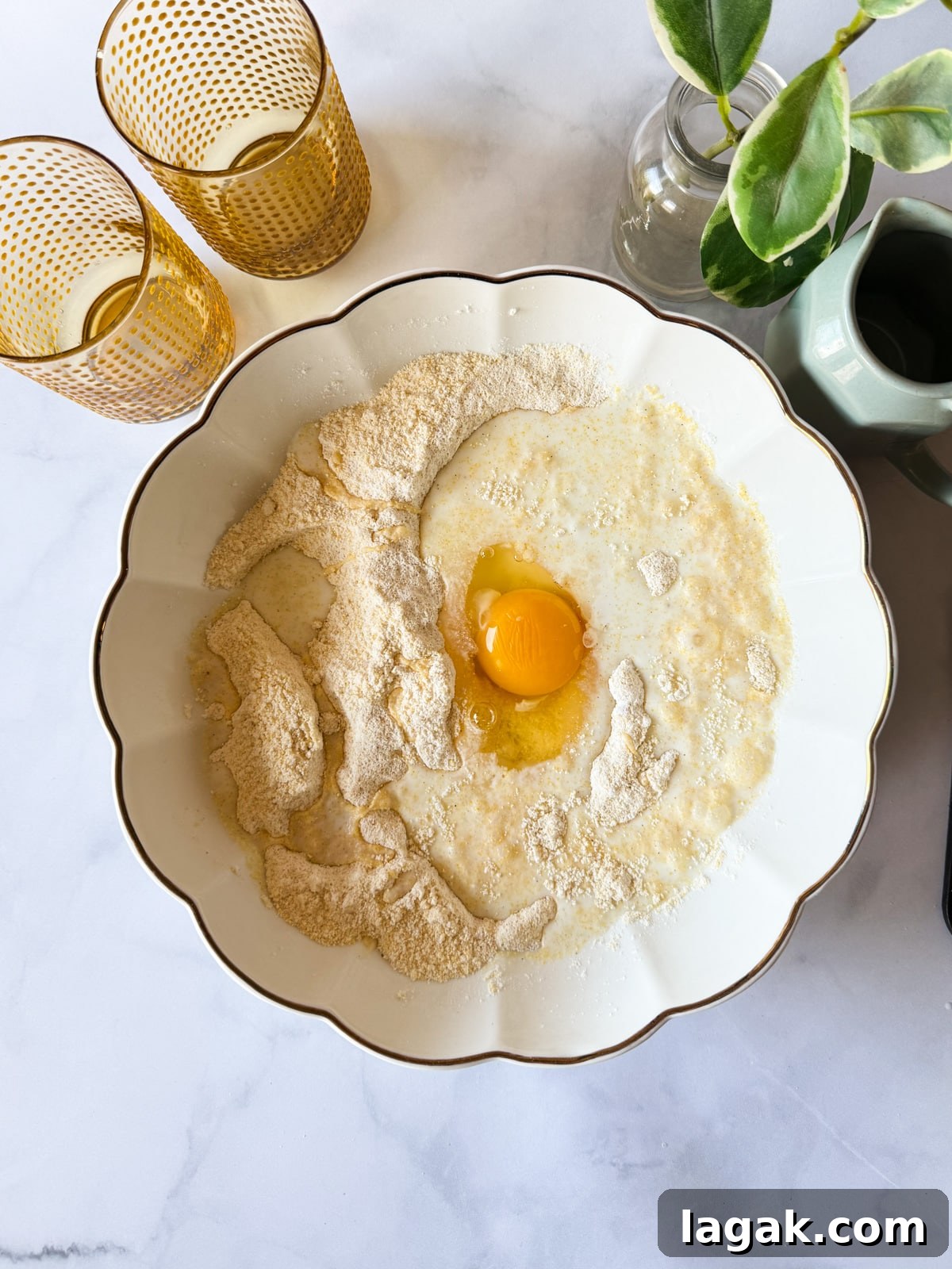 cornmeal, gluten-free flour, sugar, baking powder, and baking soda in a bowl with milk and egg on top. 