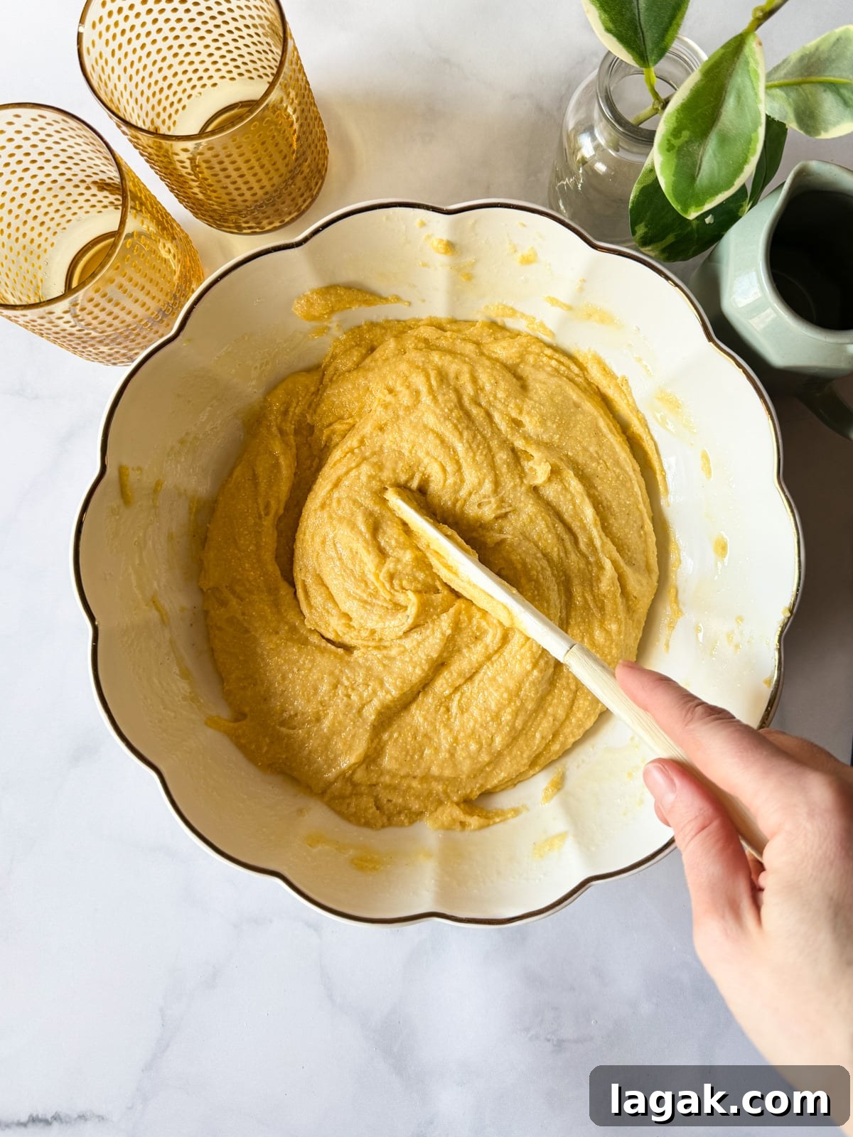 hand stirring a bowl of gluten-free cornbread batter 