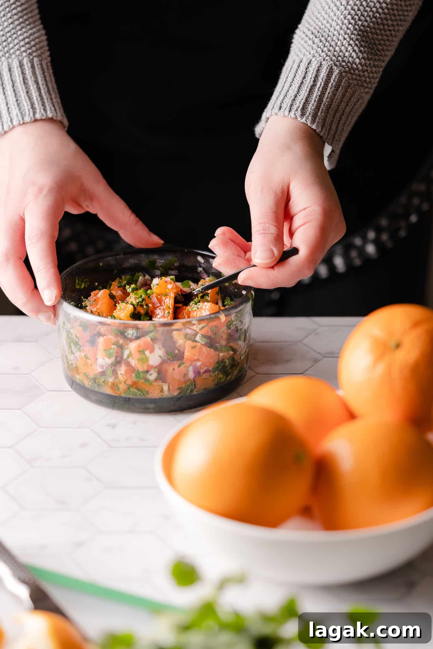 Mixing orange red onion salsa in clear bowl