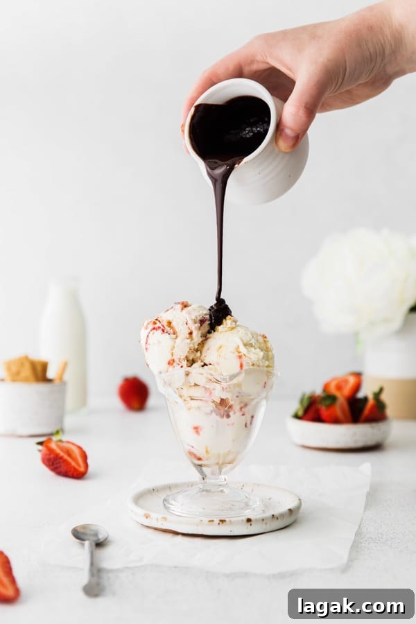 No-Churn Strawberry Cheesecake Ice Cream Recipe 3 chocolate sauce being poured over strawberry cheesecake ice cream.