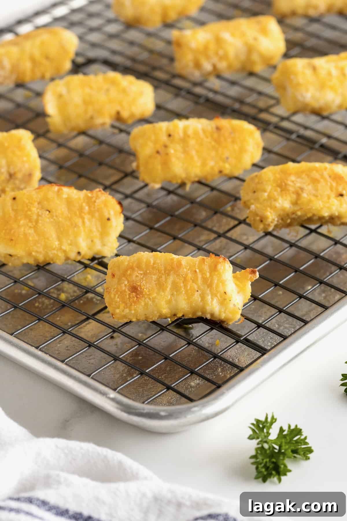 Crispy Oven-Baked Fish Sticks with Lemon Garlic Dip 13 A wire cooking rack on a baking sheet with six fish sticks on top.