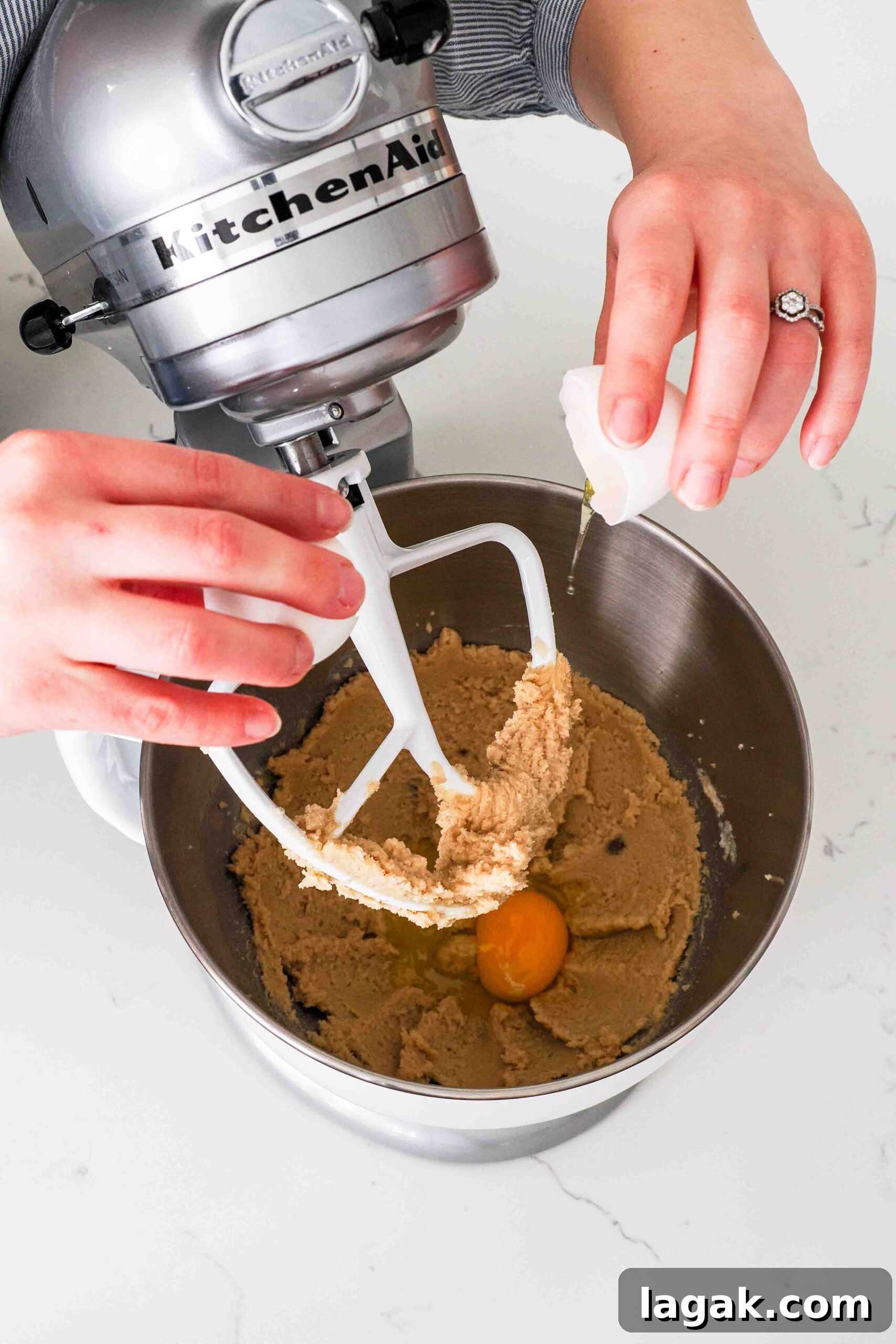 Ultimate Double Chocolate Chip Cookie Recipe for Rich, Gooey Cookies 6 Two hands crack an egg into creamed butter and sugar in a mixer bowl.