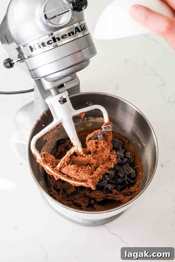 Ultimate Double Chocolate Chip Cookie Recipe for Rich, Gooey Cookies 9 Chocolate chips are poured into a mixing bowl with chocolate cookie dough.