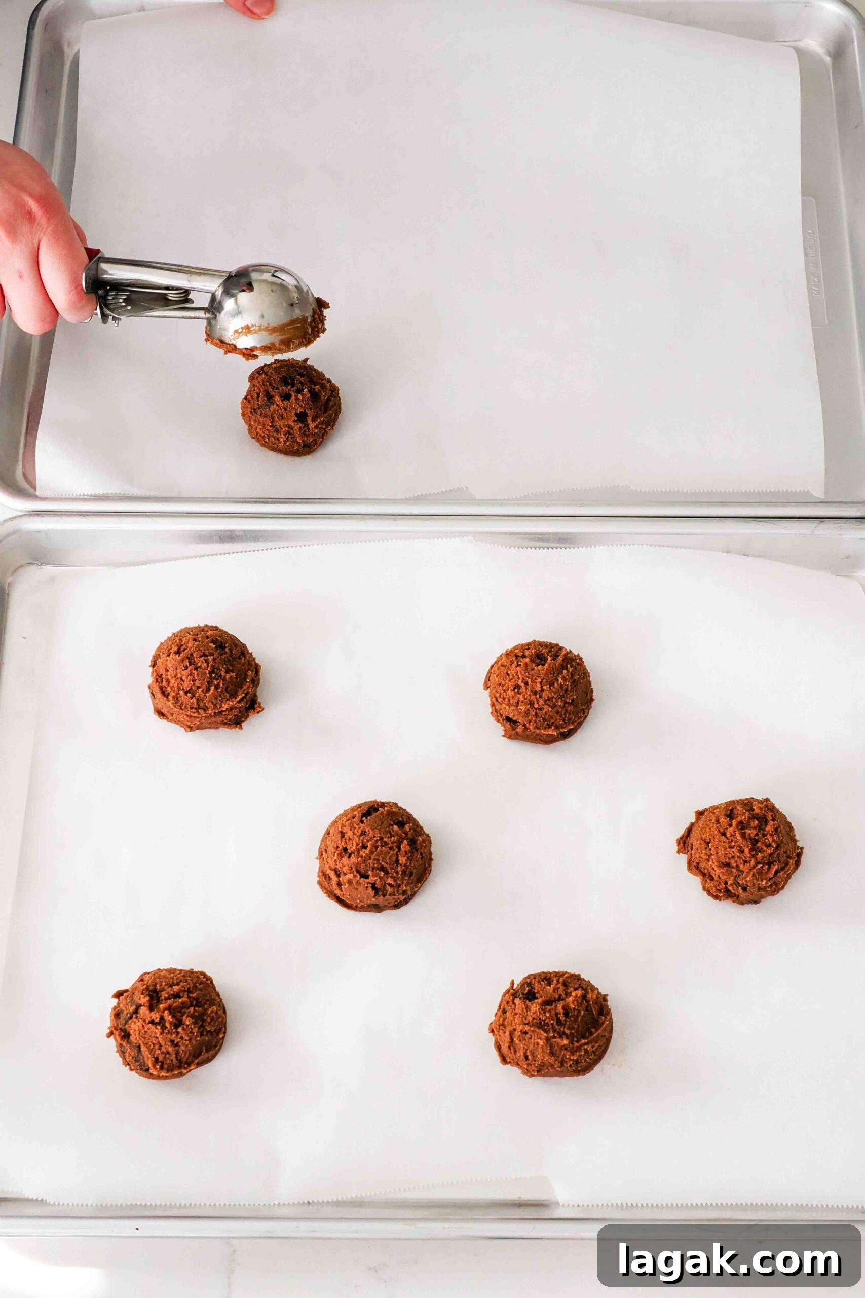 Ultimate Double Chocolate Chip Cookie Recipe for Rich, Gooey Cookies 10 A hand scoops 2" balls of chocolate cookie dough onto parchment-lined baking sheets.