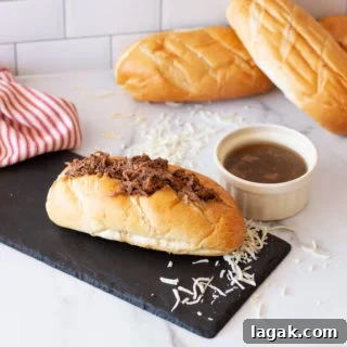 French Dip Sandwich on a counter, au jus dipping sauce and bread on counter.