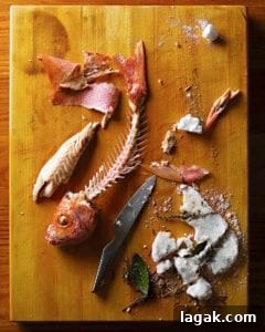 A salt-baked red snapper with all the flesh removed from the bones and a broken salt crust and knife beside the fish skeleton.