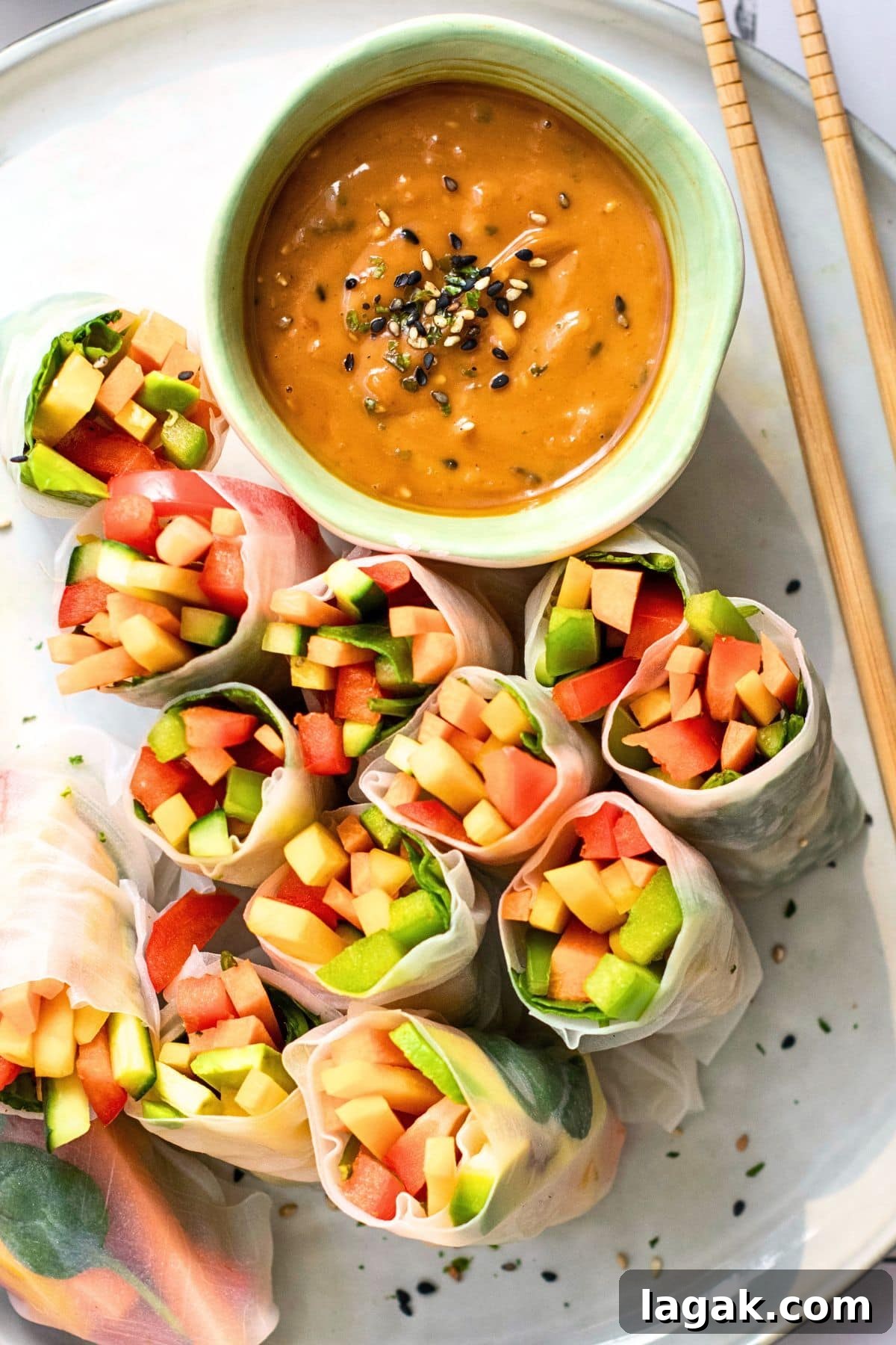Top down view of vegetarian summer rolls with a bowl of peanut sauce on a plate.