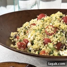 Greek Tabbouleh Salad in wooden bowl on table with water glasses