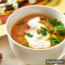 Moroccan Carrot and Cauliflower Soup in white bowl on table with sour cream and parsley.