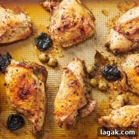 Chicken Marbella on a lined baking sheet.
