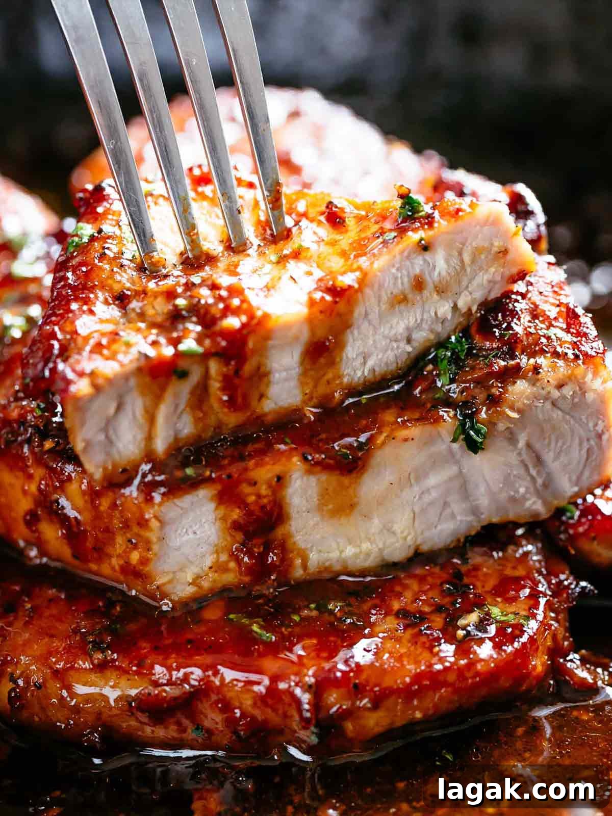 Honey Garlic Pork Chops with Sweet Glaze — Quick Weeknight Recipe 2 A stack of hot and spicy pork chops smothered in honey garlic sauce with a silver spoon pouring sauce on top.