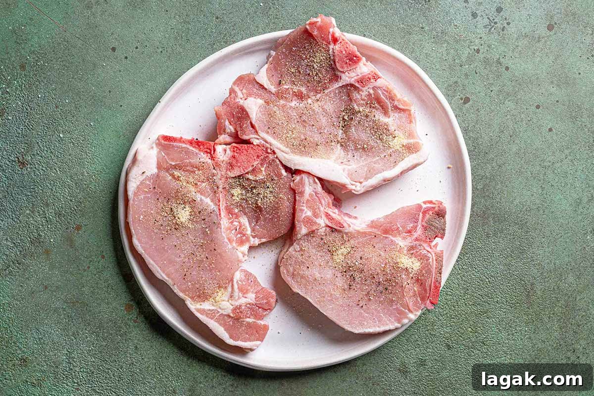 Honey Garlic Pork Chops with Sweet Glaze — Quick Weeknight Recipe 4 pork chops on a white plate seasoned with salt and pepper