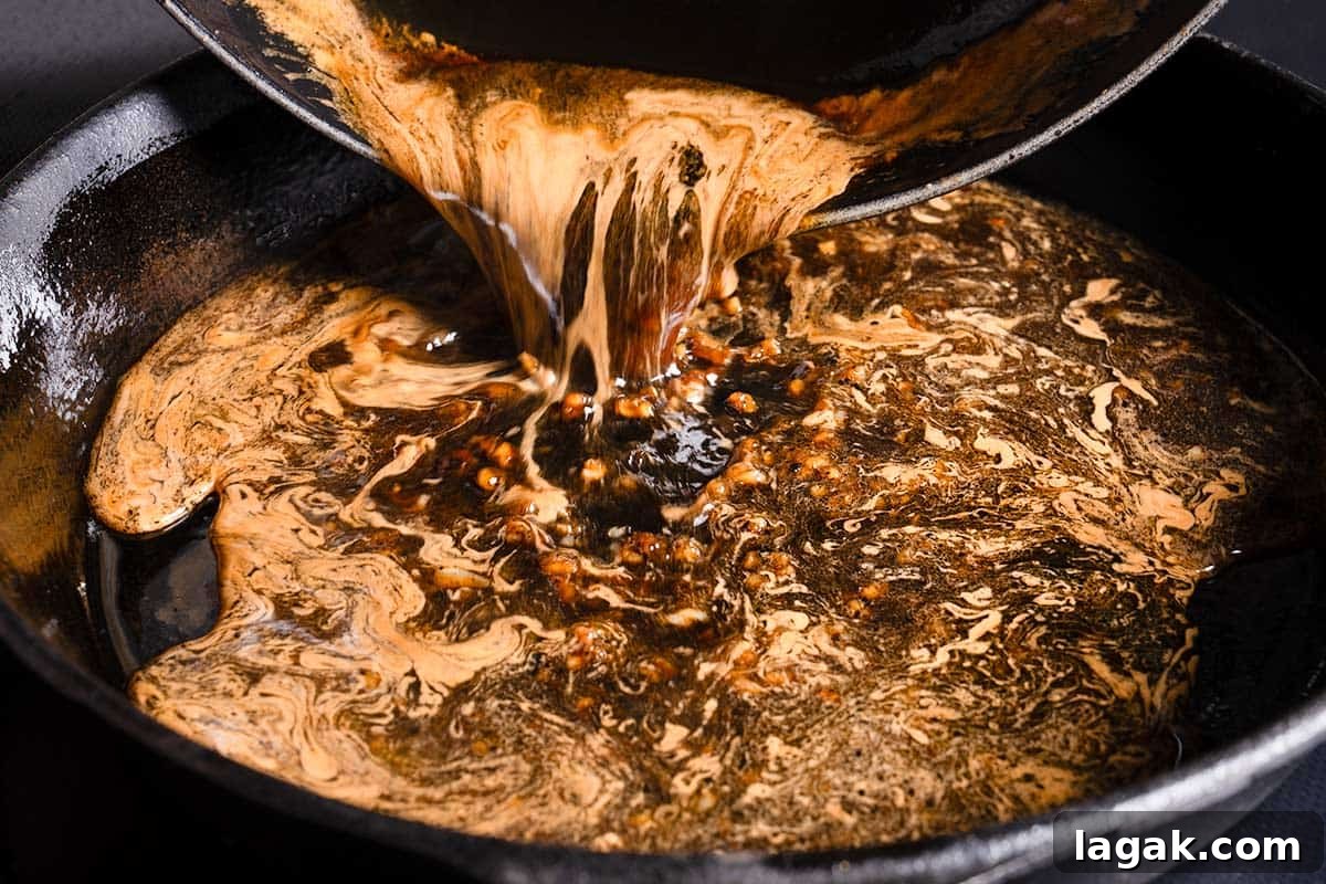 Honey Garlic Pork Chops with Sweet Glaze — Quick Weeknight Recipe 7 honey garlic sauce being poured from a bowl to a pan with browned bits from seared pork chops