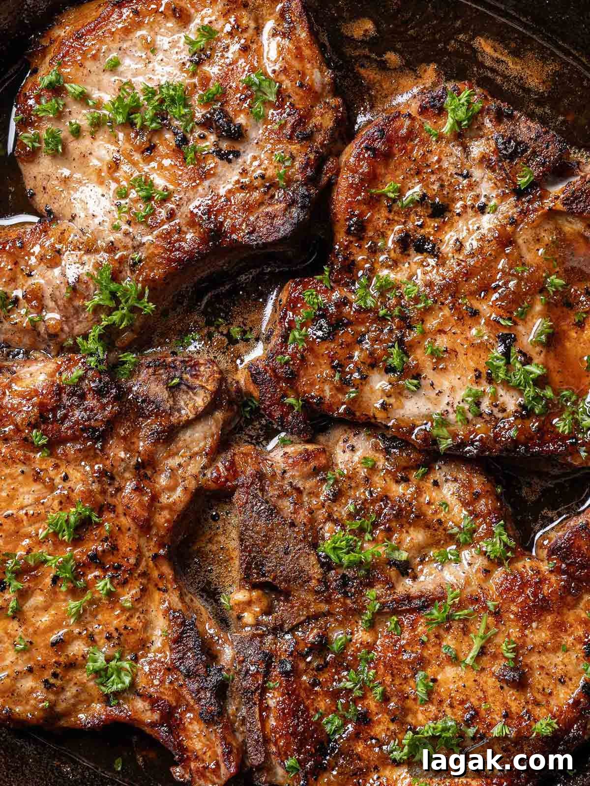 Honey Garlic Pork Chops with Sweet Glaze — Quick Weeknight Recipe 9 finished juicy honey garlic pork chops in a black pan garnished with parsley
