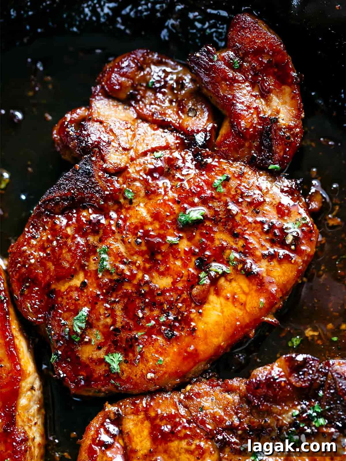 Honey Garlic Pork Chops with Sweet Glaze — Quick Weeknight Recipe 10 finished juicy honey garlic pork chops in a black pan garnished with parsley